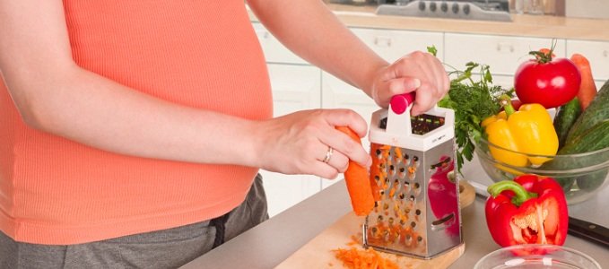 Femme enceinte râpant des carottes